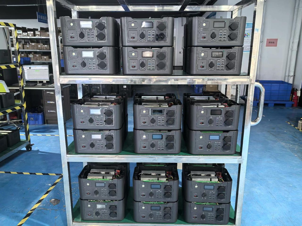 Batch of portable power stations on a production rack, assembled units and open chassis showing internal battery packs